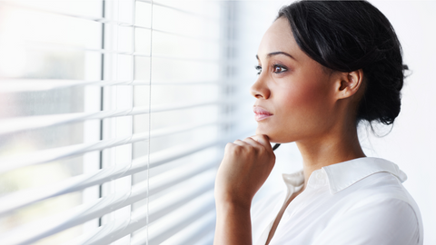 A woman in thought while looking out an office window