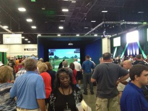 Attendees of the World Amateur Golf Championships walking around ace indoor golf simulator