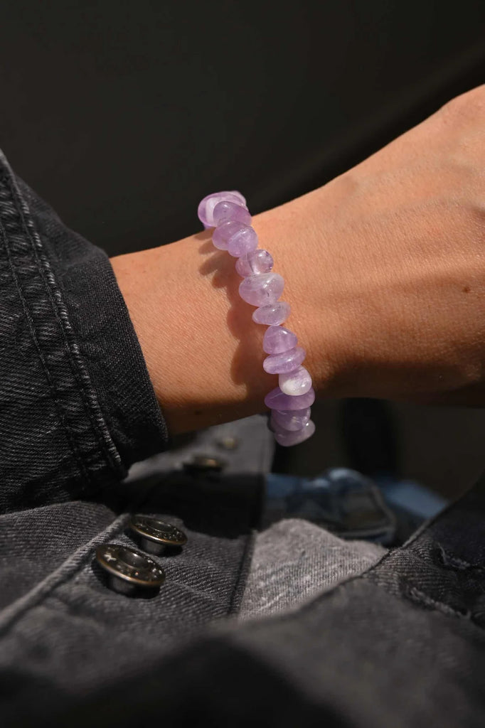 Bracelet on a woman's wrist featuring small, 8-10mm amethyst chip gemstone beads on an elastic band