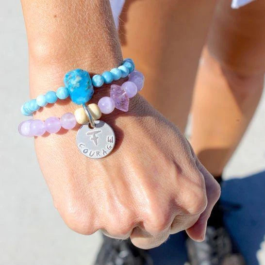 Amethyst crystal courage bracelet on proud fist worn alongside a turquoise bracelet