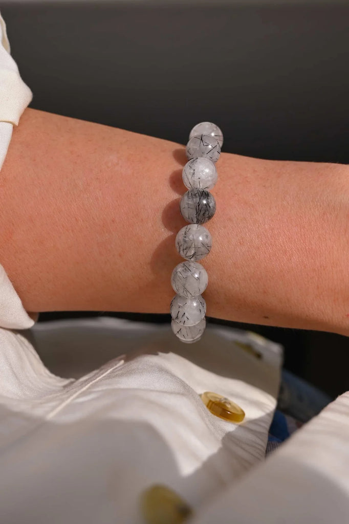 woman wearing bracelet of 10mm black tourmaline rutilated quartz gemstone beads