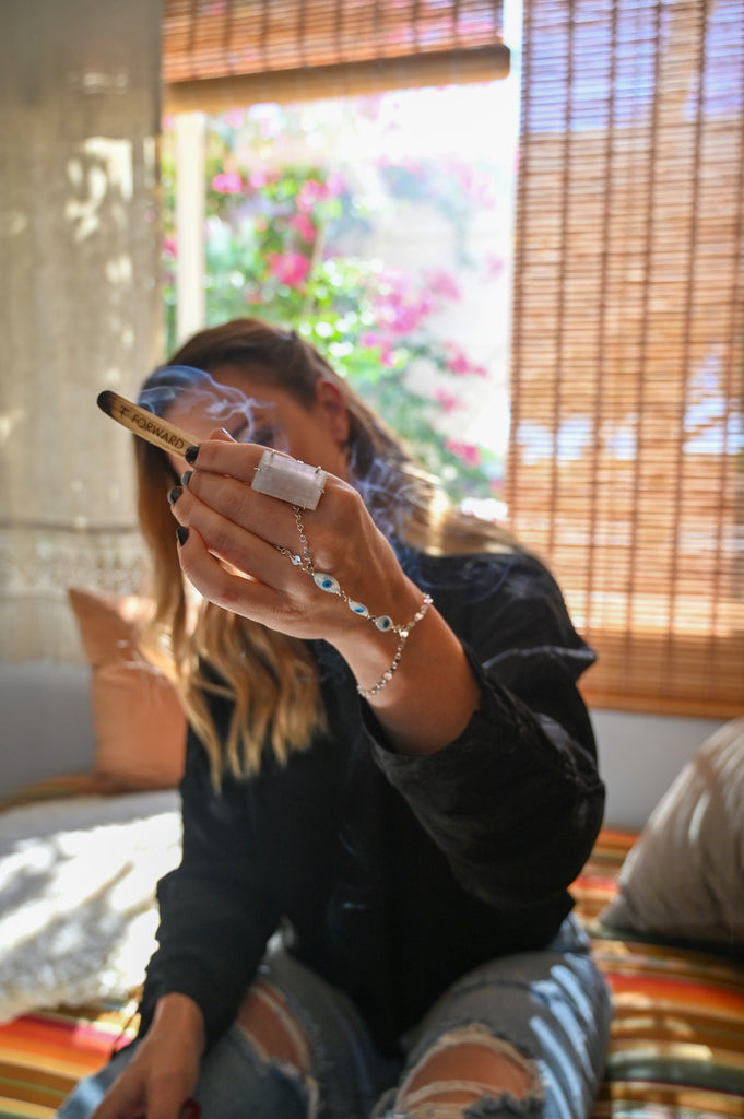 girl holding palo santo smoking crystal jewelry on 