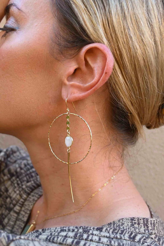 Woman wearing gold hoop earrings adorned with moonstone crystals for self love