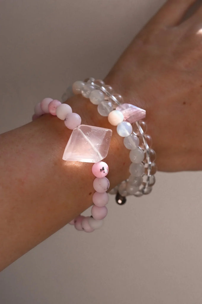 Three pink opal and rose quartz bracelets worn on a woman's wrist