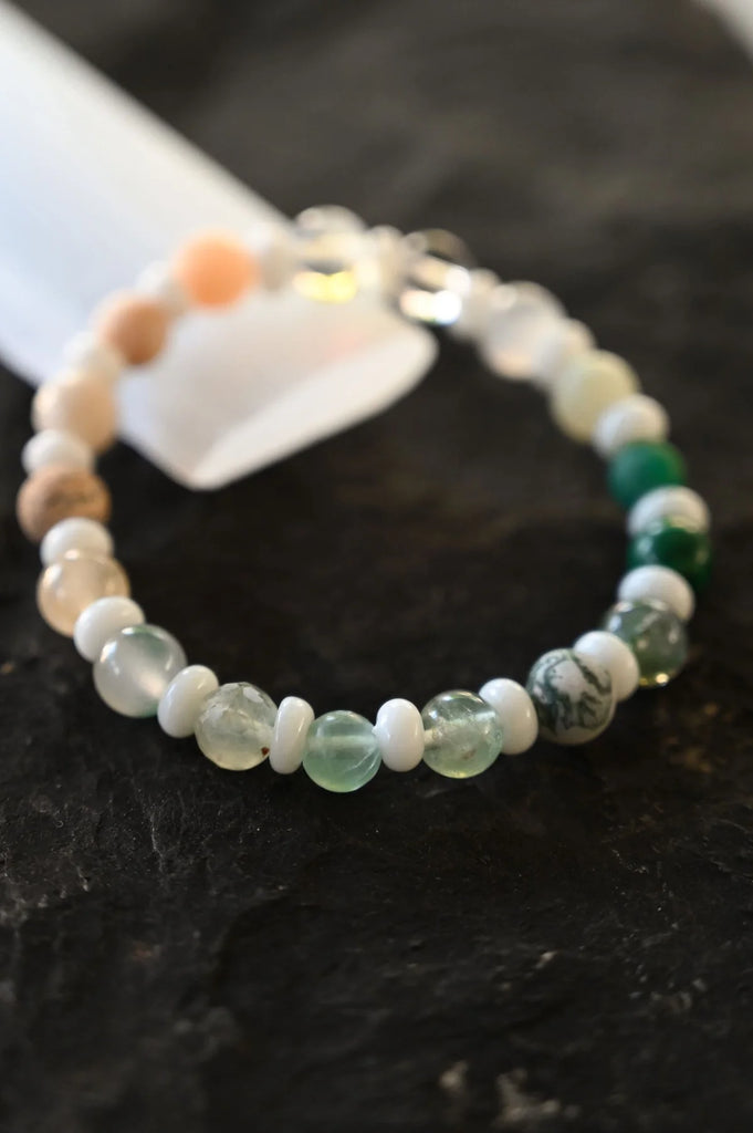 varied 6-8mm gemstone beads in shades of green, blue, and pink on an elastic band. stones include sunstone, amethyst, selenite, quartz, amazonite, lapis, tiger's eye, rose quartz, jade & citrine