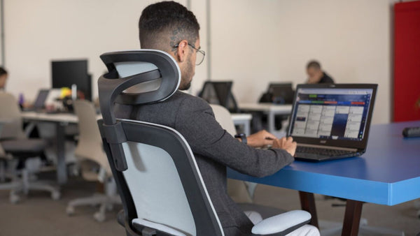 Homem no ambiente de trabalho usando cadeira ergonômica.