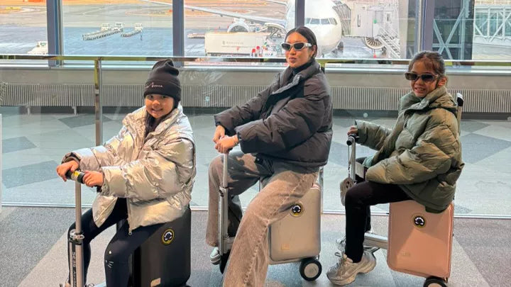 three girls ride airwheel se3s rideable luggage in the airport