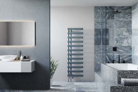 A modern dual-fuel towel rail in grey with two long vertical pipes and twelve horizontal panels, in a chic bathroom with blue tiling and a mosaic-style bathtub.