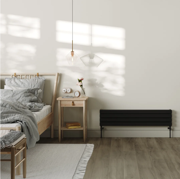 An image of a black radiator placed next to a bedside cabinet