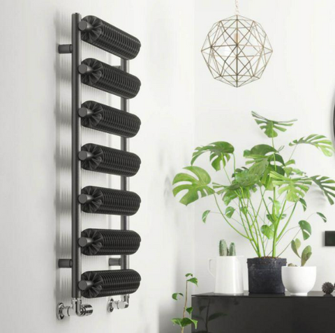 An edgy industrial style Ribbon towel rail mounted on a wall beside a console table holding green plants.