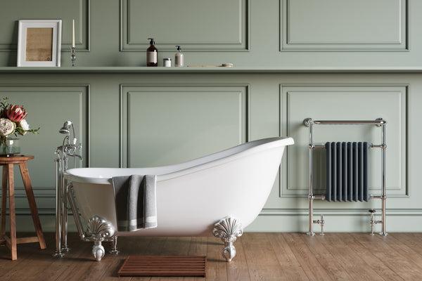 A classical bathroom with soft green walls, featuring a freestanding bathtub and a vintage-style radiator with a steel frame.