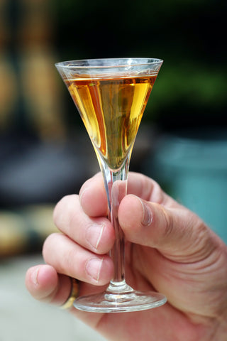 A hand holding a glass of aquavit