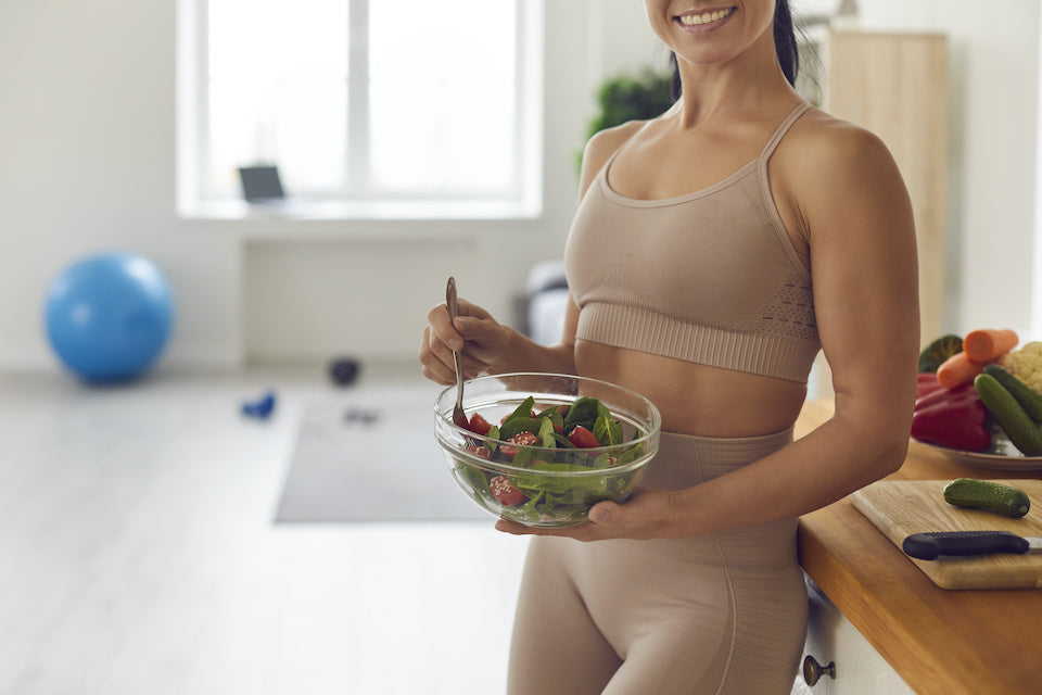 Healthy woman eating a salad after a workout. 
