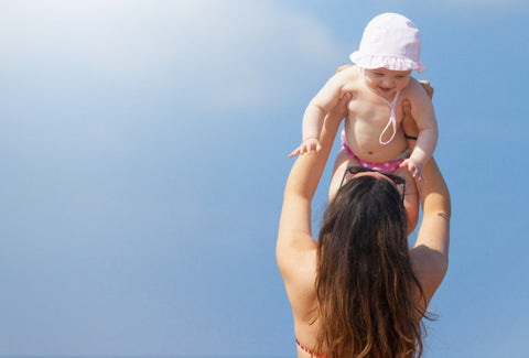 Mother with baby at beach holding baby up in the air