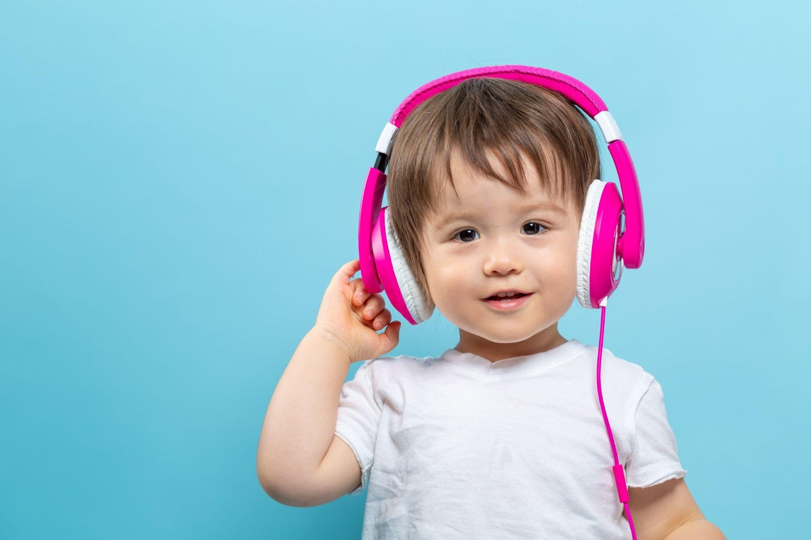 A young boy wearing headphones on a blue background, enjoying his music