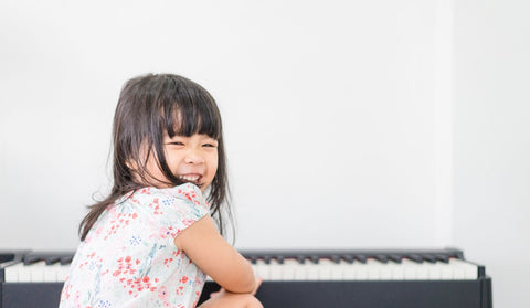 A young girl sitting on a piano, exploring the world of Classical Music, stimulating her developing mind