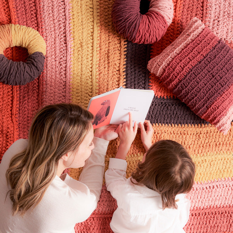 Mom and daughter reading a book on a blanket