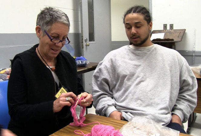 Lynn teaching inmate to knit