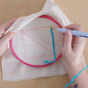 Step 4: Ring on cloth, woman's hand holding punch needle and making designs