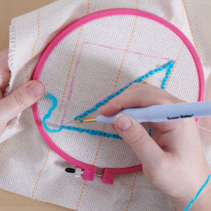 Step 4: Ring on cloth, woman's hand holding punch needle and making designs