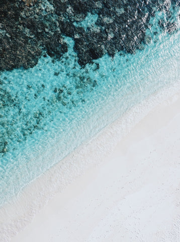 Weißer Sandstrand und türkis blaues Meerwasser mit Felsen