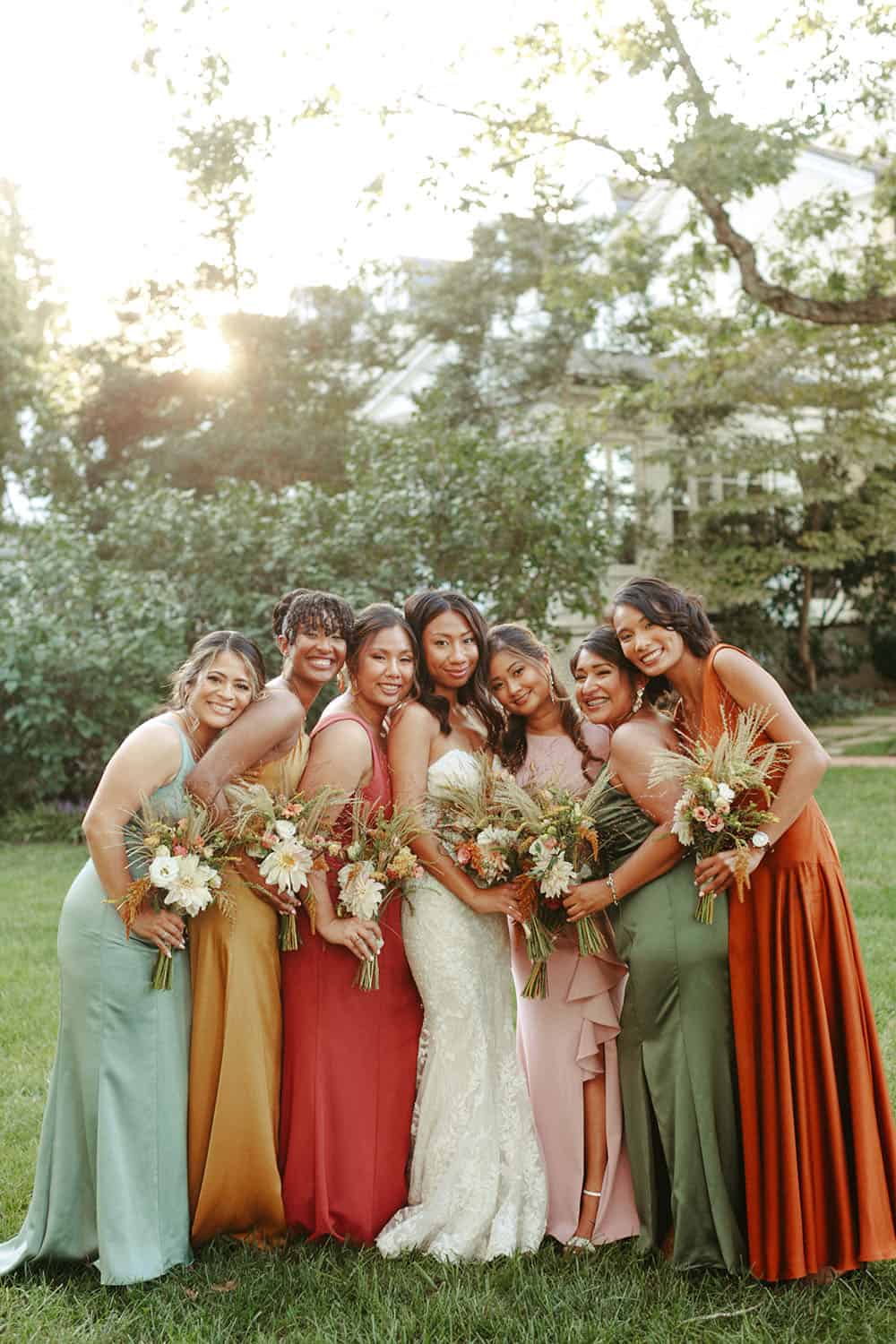 Bridesmaids in different colored sunset themed dresses