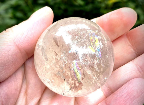 Wendy's hand holding rainbow filled clear quartz sphere