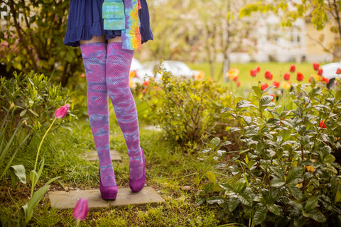 Model wearing tie dyed thigh high socks standing in a garden full of tulips