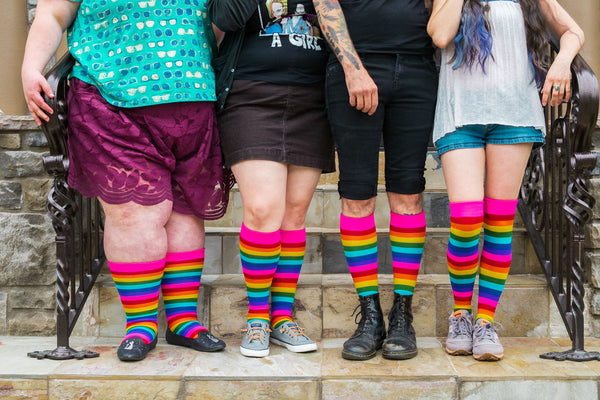 Pride Stripes Knee High Socks in the pink rainbow colorway shown on four models of varying sizes