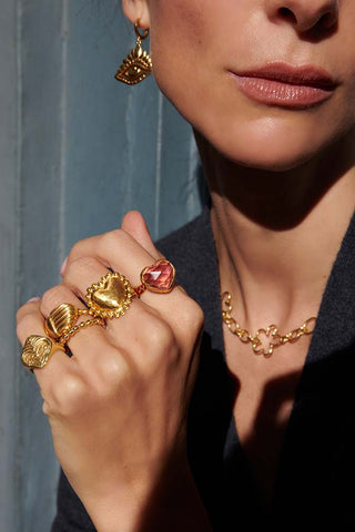 Woman wearing rings on every finger and gold chain necklace.