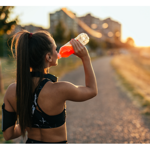 Woman drinking electrolyte beverage from bottle.