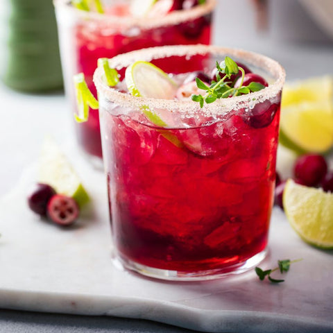 Two glasses of cranberry with lime slices and garnishes and a refreshing Cranberry Cosmo Spritzer.