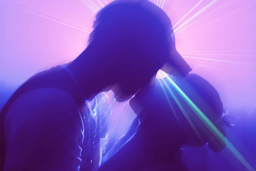 A silhouette of two people kissing, backlit with a purple light.