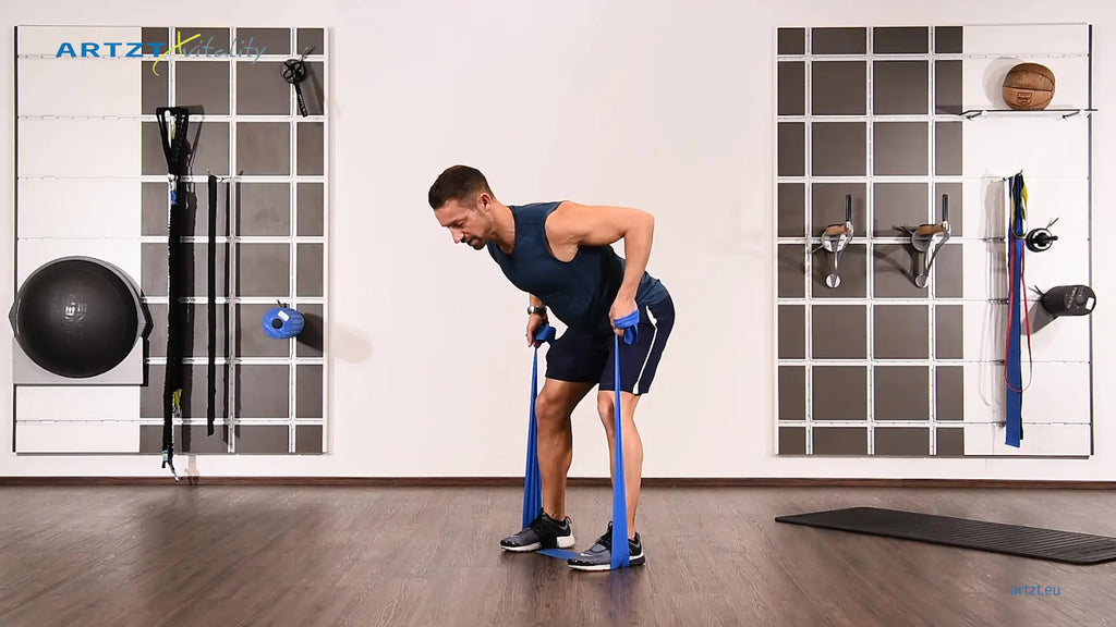 Man performs the standing rowing exercise with a TheraBand.