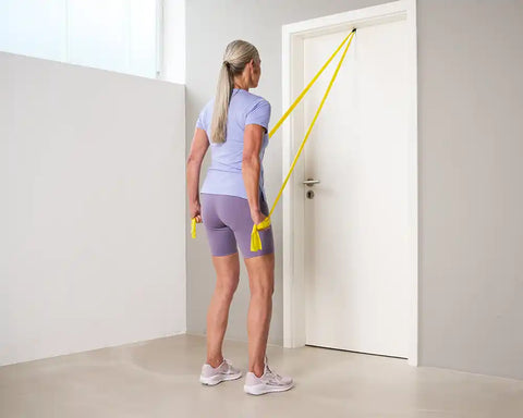 Woman doing triceps and strong back exercise with a TheraBand - final position