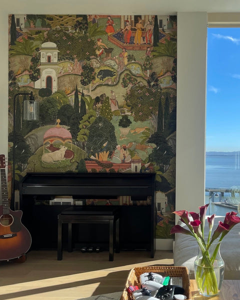 A vibrant Indian mural behind a piano, guitar, and alongside a sunny skyline view