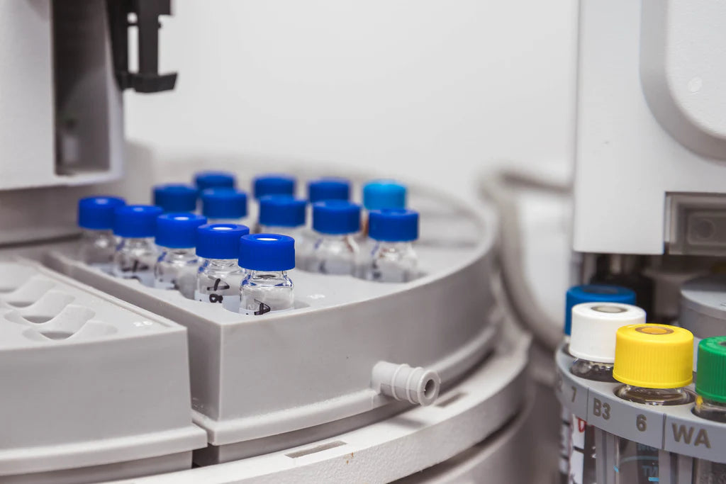 Automated laboratory equipment with capped sample vials arranged in a tray