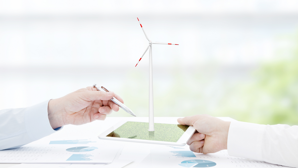 two hands holding an tablet with a solar wind mill on top