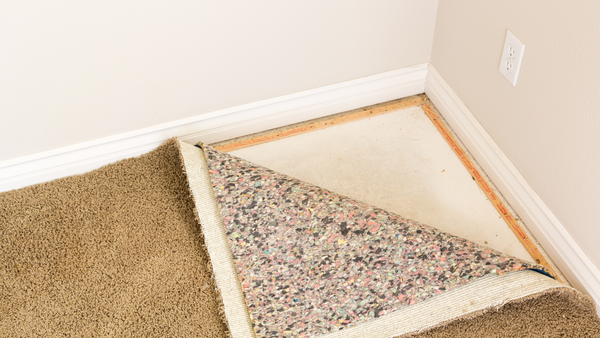 Corner of carpet flipped over showing carpet backing