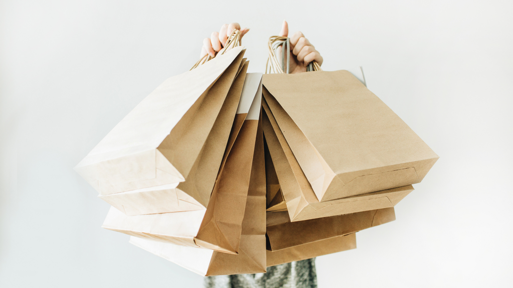 person holding up brown paper shopping bags
