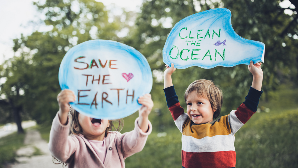 two children holding up handmade signs to save our earth and ocean