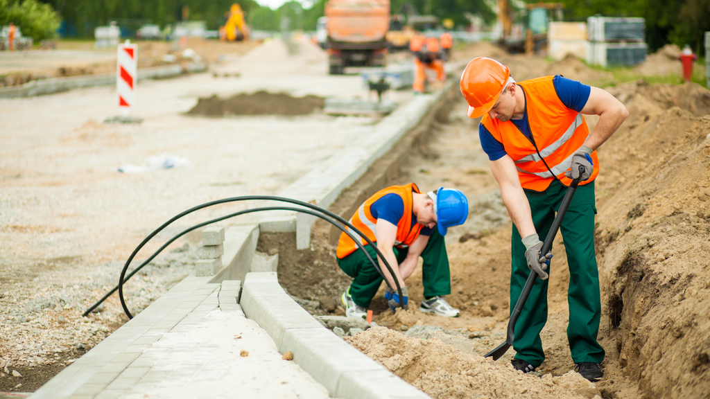 two construction workers wearing orange vests and working on a project