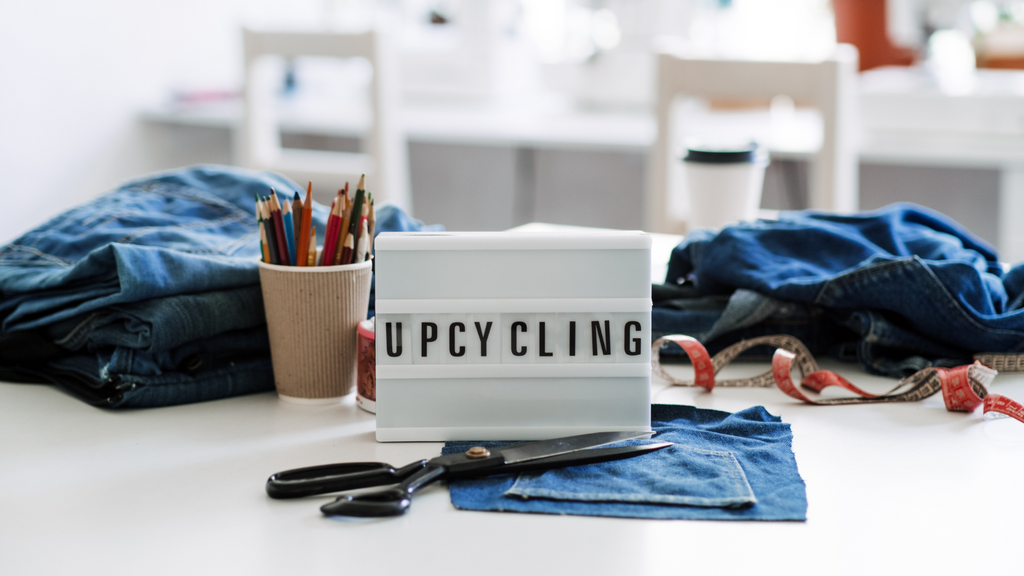 multiple pairs of denim on the the table with a sign that read "upcycling"