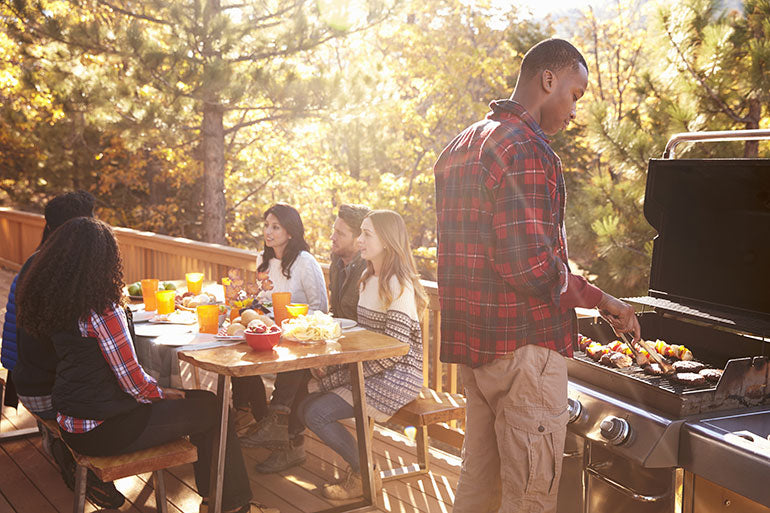 Group of people on wooden deck with barbeque grill