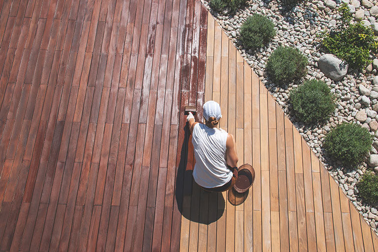 Woman applying stain to wooden deck