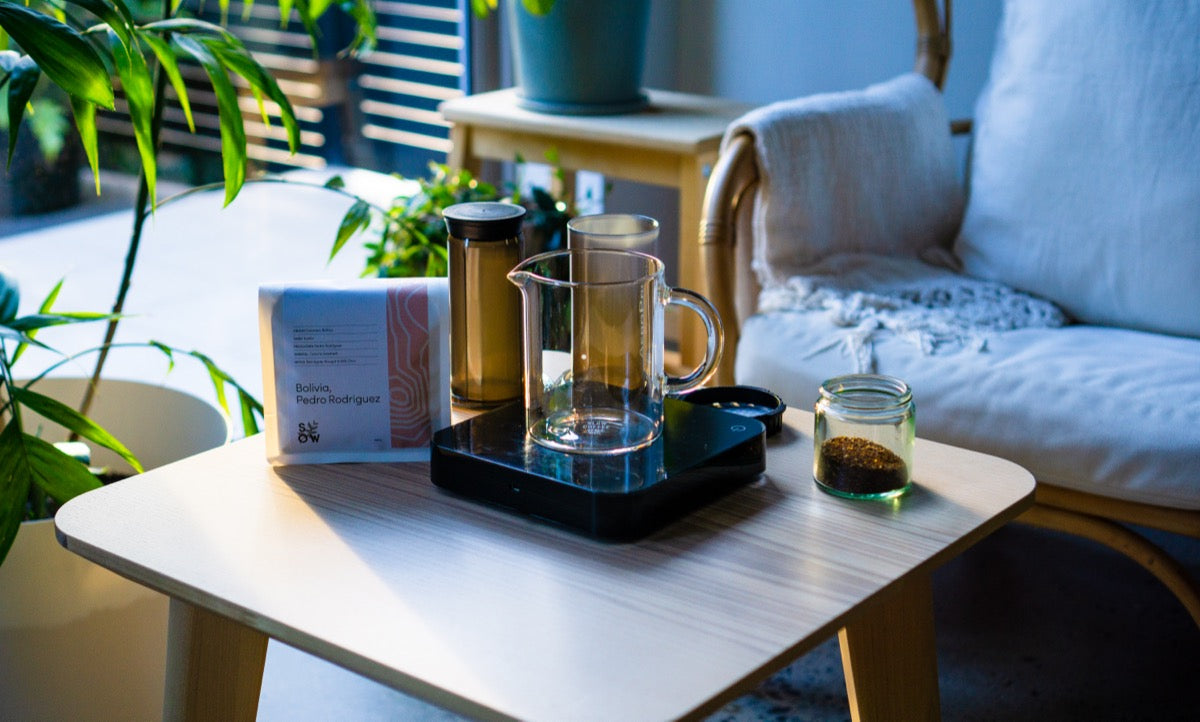 An Aeropress, scales, jug, and Sow coffee arranged on a coffee table: everything you need to prepare great coffee.