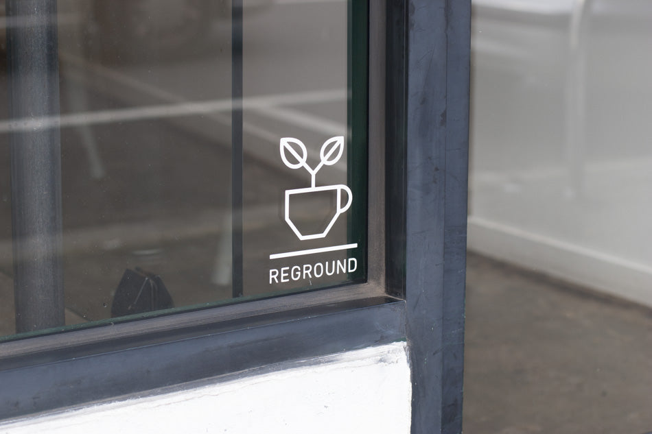A coffee shop window sports the Reground logo: a young plant growing in a cup.