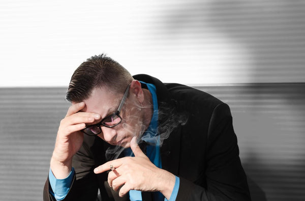  A man dealing with nicotine headache while smoking