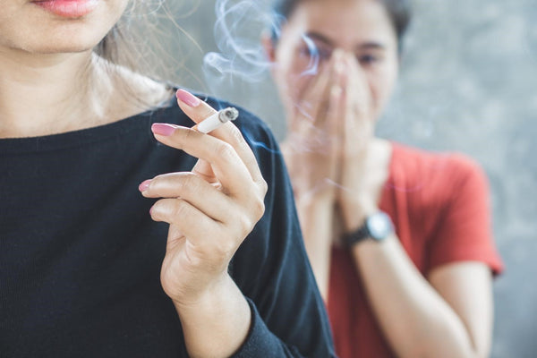 One girl's cigarette smoke is negatively impacting another girl.