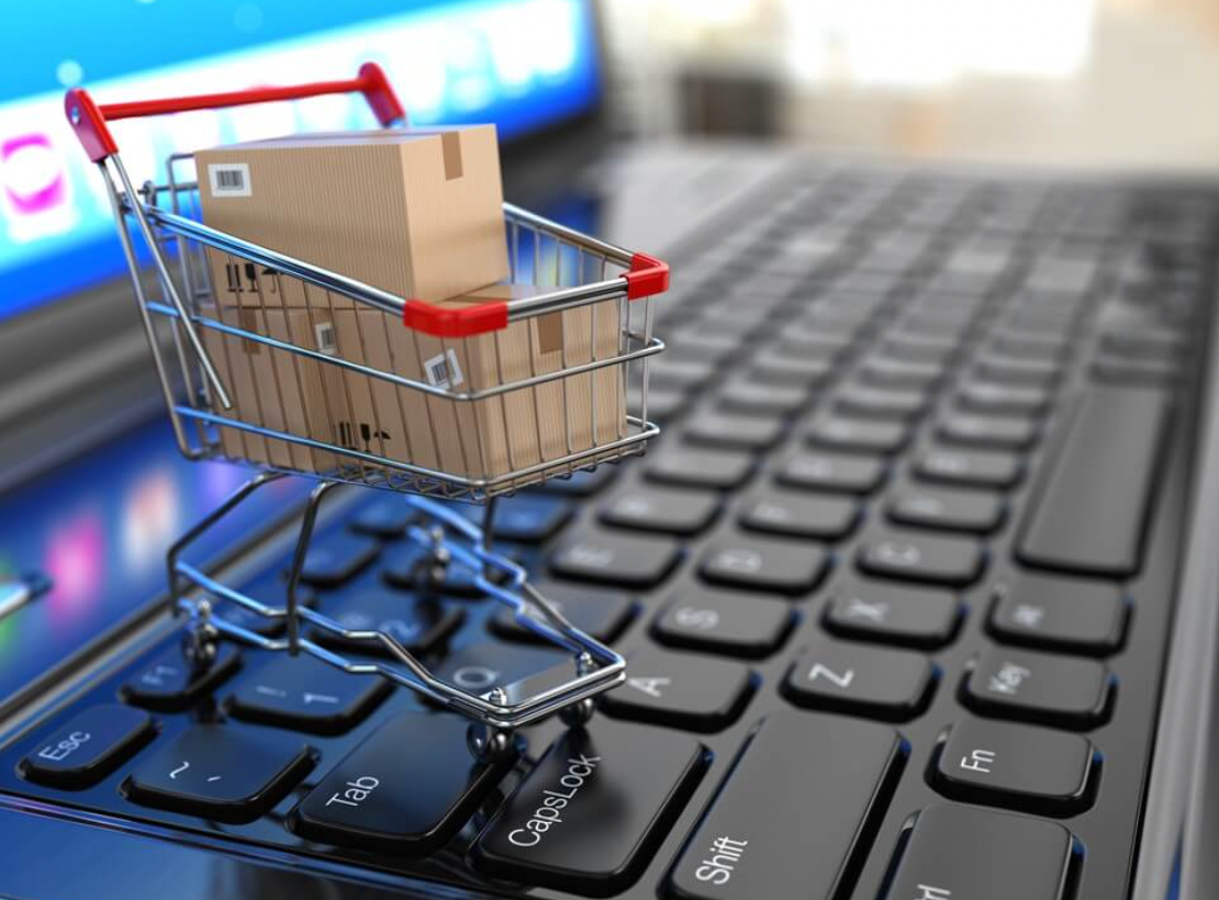 A mini shopping cart on top of a laptop keyboard.